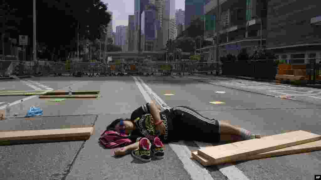 Seorang pelajar yang ikut berdemonstrasi tidur di tengah jalan di Hong Kong (5/10). (AP/Wally Santana)