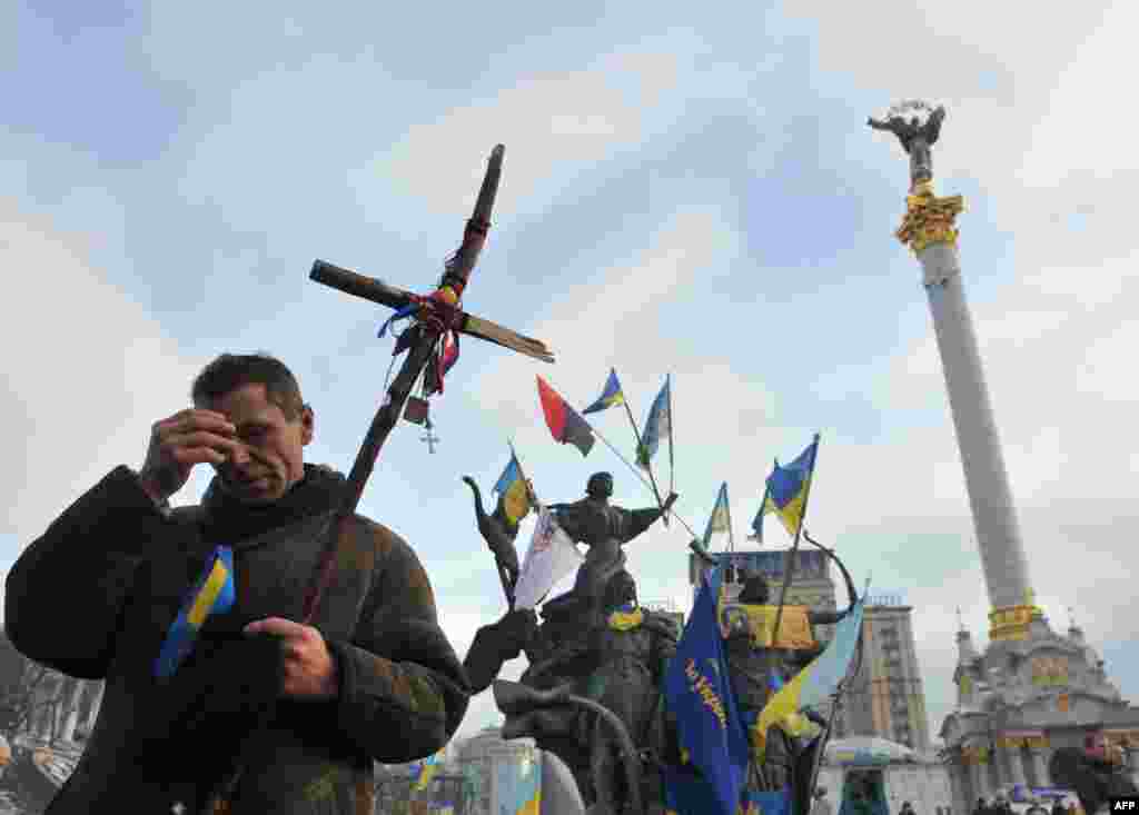 Seorang pengunjuk rasa pro-Eropa membuat tanda salib di keningnya dalam sebuah upacara keagamaan di Lapangan Kemerdekaan di Kiev. Untuk pertama kalinya kelompok oposisi Ukraina berunding dengan dengan Presiden Yanukovych pada hari Jumat sejak protes masal pecah tiga minggu yang lalu.