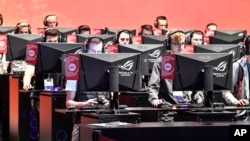 FILE - In this Aug. 20, 2019 file photo, gamers play the latest video games from Electronic Arts at the Gamescom in Cologne, Germany. 