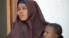 FILE - A Somali woman, who was sentenced to a year in jail after she told a reporter she was raped by security forces, holds her baby at the court house in Mogadishu, March 3, 2013.