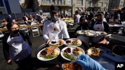 ARCHIVO - Voluntarios de la comunidad se preparan para servir comida gratuita de Acción de Gracias mientras la fiesta anual del distrito Skid Row de Los Ángeles acoge a miles de personas sin hogar y necesitadas en el centro de Los Ángeles, el jueves 24 de noviembre de 2022.