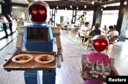 Pasangan robot Xiaolan (kiri) dan Xiaotao membawa nampan makanan di sebuah restoran di Jinhua, Provinsi Zhejiang, Cina. (Foto: Reuters)