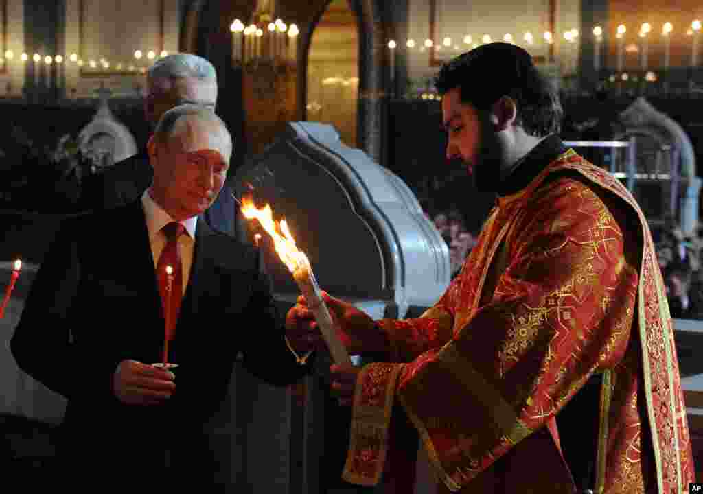 Russian President Vladimir Putin, foreground left, attends the Easter service in Christ the Savior Cathedral in Moscow, April 20, 2014. 