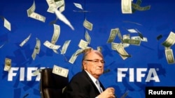 British comedian Lee Nelson (unseen) throws banknotes at FIFA President Sepp Blatter as he arrives for a news conference after the Extraordinary FIFA Executive Committee Meeting in Zurich, Switzerland, July 20, 2015.