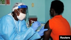 Un trabajador de la salud inyecta la vacuna a una voluntaria en Liberia. 