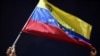 Un hombre muestra una bandera venezolana en protesta junto a familiares y amigos de migrantes venezolanos que murieron cuando se hundió un barco que los transportaba a Trinidad y Tobago, en Güiria, Venezuela, el 18 de diciembre de 2020.