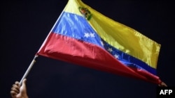 Un hombre muestra una bandera venezolana en protesta junto a familiares y amigos de migrantes venezolanos que murieron cuando se hundió un barco que los transportaba a Trinidad y Tobago, en Güiria, Venezuela, el 18 de diciembre de 2020.