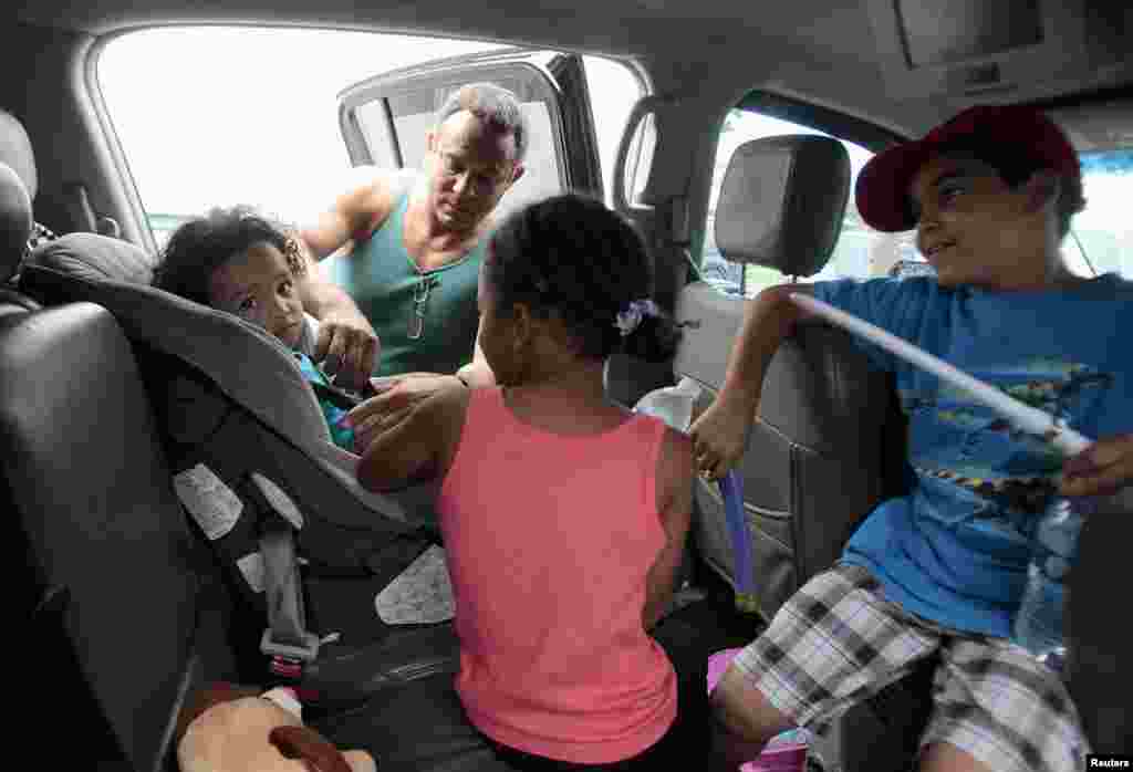 Estanislao Fabian straps Jaden Fabian (L), 1, into her car seat by as her family evacuates their home as Tropical Storm Isaac heads towards the Louisiana coast line in Oakville, Louisiana, August 28, 2012.