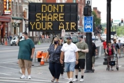 FILE - A sign encouraging the wearing of masks and adhering to social distancing stands at a street corner in downtown Nashville, Tenn., Aug. 5, 2020.