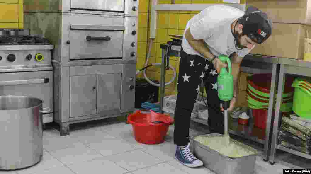 Hassan Mansour dari Aleppo, Suriah, mempersiapkan makanan sehari-hari di pusat komunitas Khora, di distrik Exarchia di Athena, Yunani (24/10).