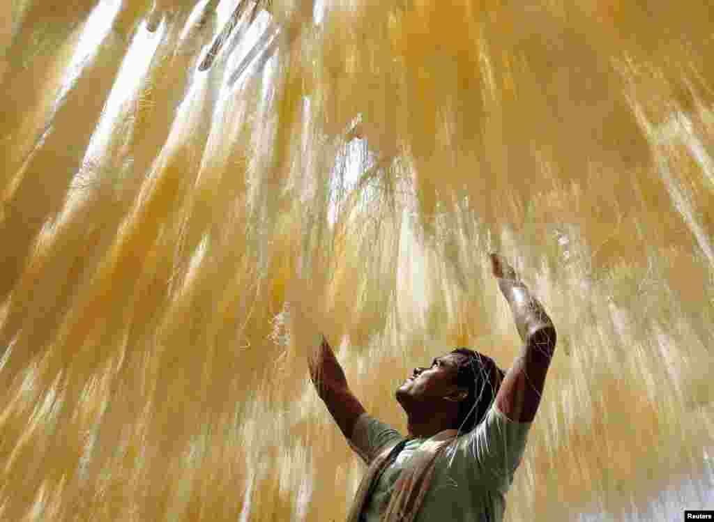 Seorang pekerja mengeringkan bihun di Allahabad, India utara.