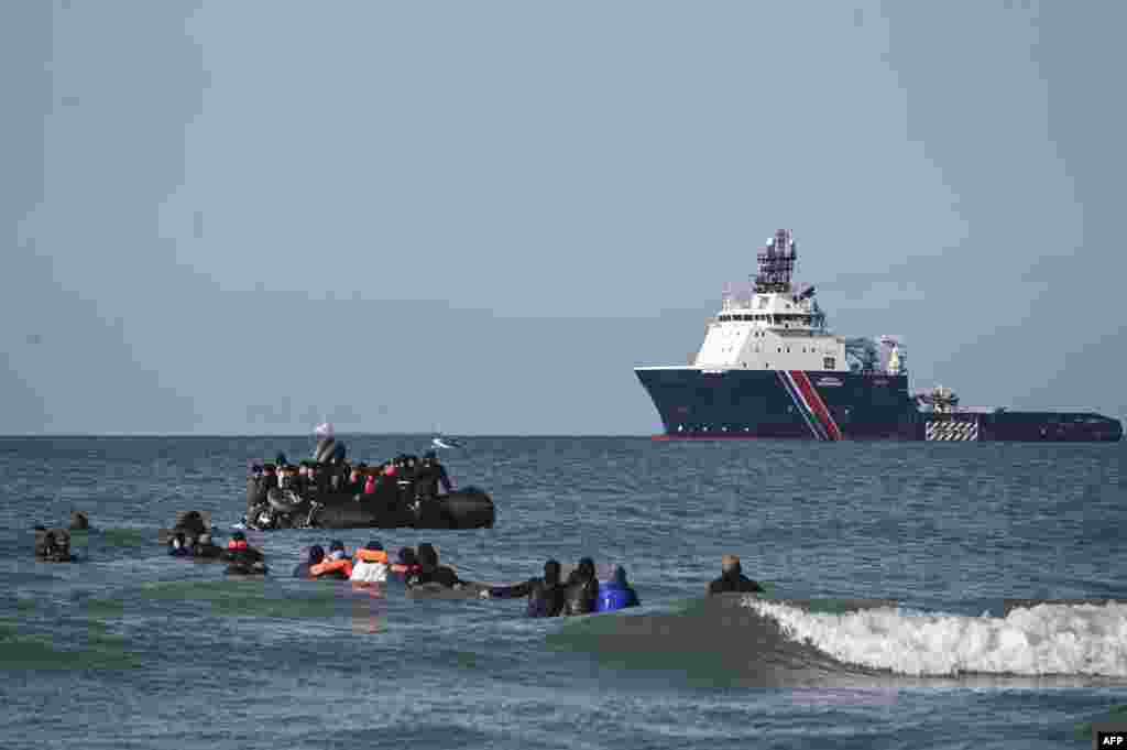 Migrants swim to board a smugglers' boat in order to attempt crossing the English Channel off the beach of Audresselles, northern France.
