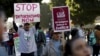 FILE - People hold signs as they gather outside a Federal Building while protesting against Immigration and Customs Enforcement (ICE) raids on Central American refugees in Los Angeles, California, Jan. 26, 2016.