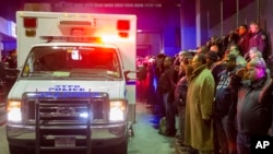 人们在运送两位被杀警员遗体的车辆旁默哀