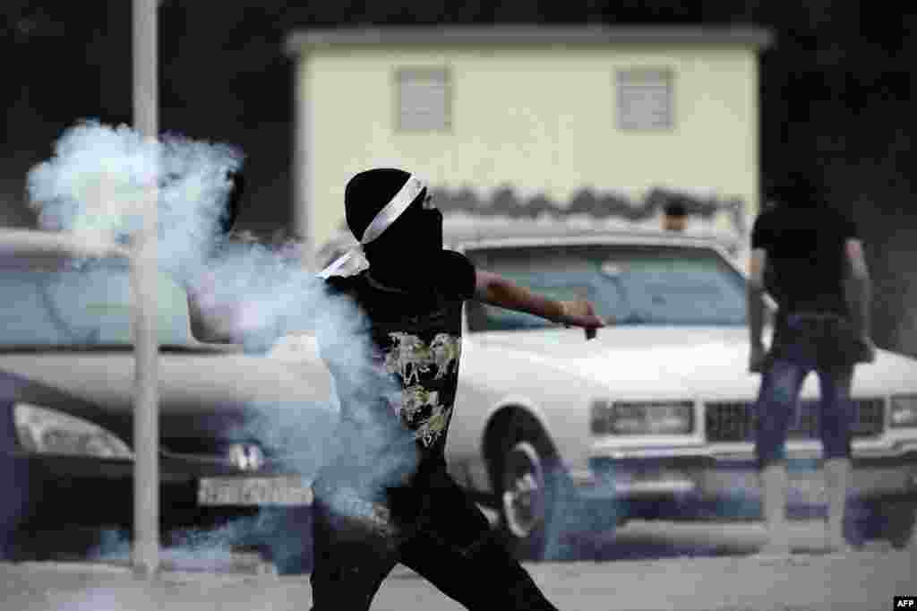 Seorang protestor Bahrain melempar kembali tabung gas air mata dalam bentrokan dengan polisi anti huru-hara menyusul kerusuhan demo anti-rezim berkuasa menuju 'Pearl Square' setelah acara keagamaan yang menandai hari Asyura di desa Daih, Bahrain.