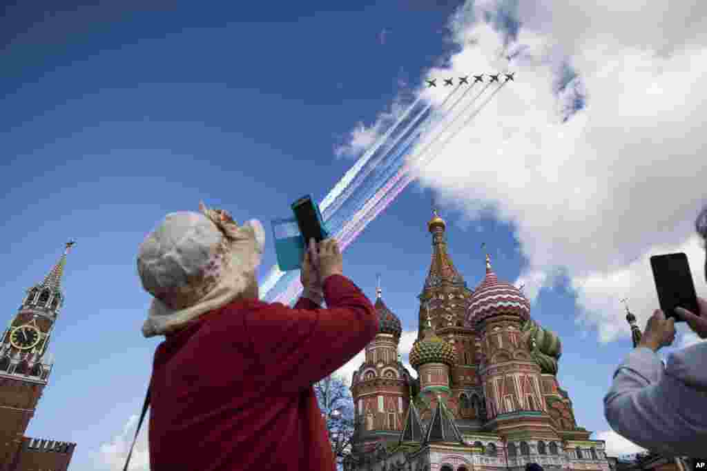 Seorang turis memotret jet-jet Rusia yang terbang di atas Kremlin dalam latihan parade militer untuk Hari Kemerdekaan di Moskow. 
