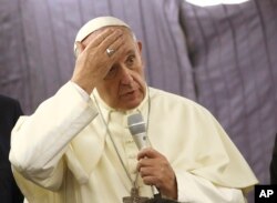 Pope Francis touches his forehead as he talks with journalists during his flight from Lima, Peru, to Rome, Italy, Jan. 21, 2018.