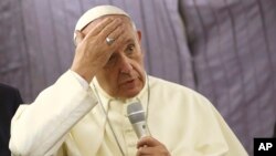 Pope Francis touches his forehead as he talks with journalists during his flight from Lima, Peru, to Rome, Italy, Jan. 21, 2018. 