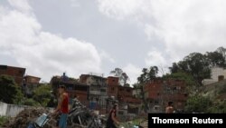 Personas cargan contenedores plásticos para recolectar agua acumulada en túneles de construcción en El Avila, cerca de Caracas.