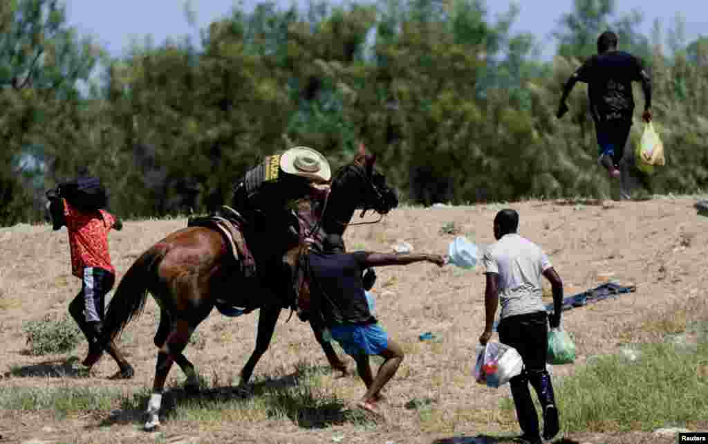A U.S. border patrol officer grabs the shirt of a migrant trying to return to the United States along the Rio Grande river, after having crossed from the United States into Mexico to buy food, as seen from Ciudad Acuna, in Ciudad Acuna, Mexico, Sept 19, 2021.