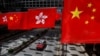 一辆出租车行驶在香港街道，一旁的购物中心外悬挂了香港旗帜和中国国旗。（路透社，2023年7月5日）