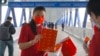 一名支持北京政府的女子在香港人行道上发放中国国旗。（2021年4月15日）