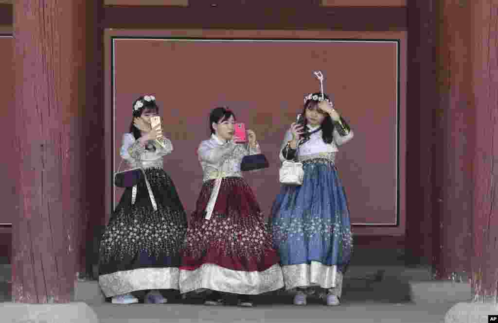 Tiga perempuan mengenakan pakaian tradisional "Hanbok" merapikan rambut mereka di istana Gyeongbok di Seoul, Korea Selatan.