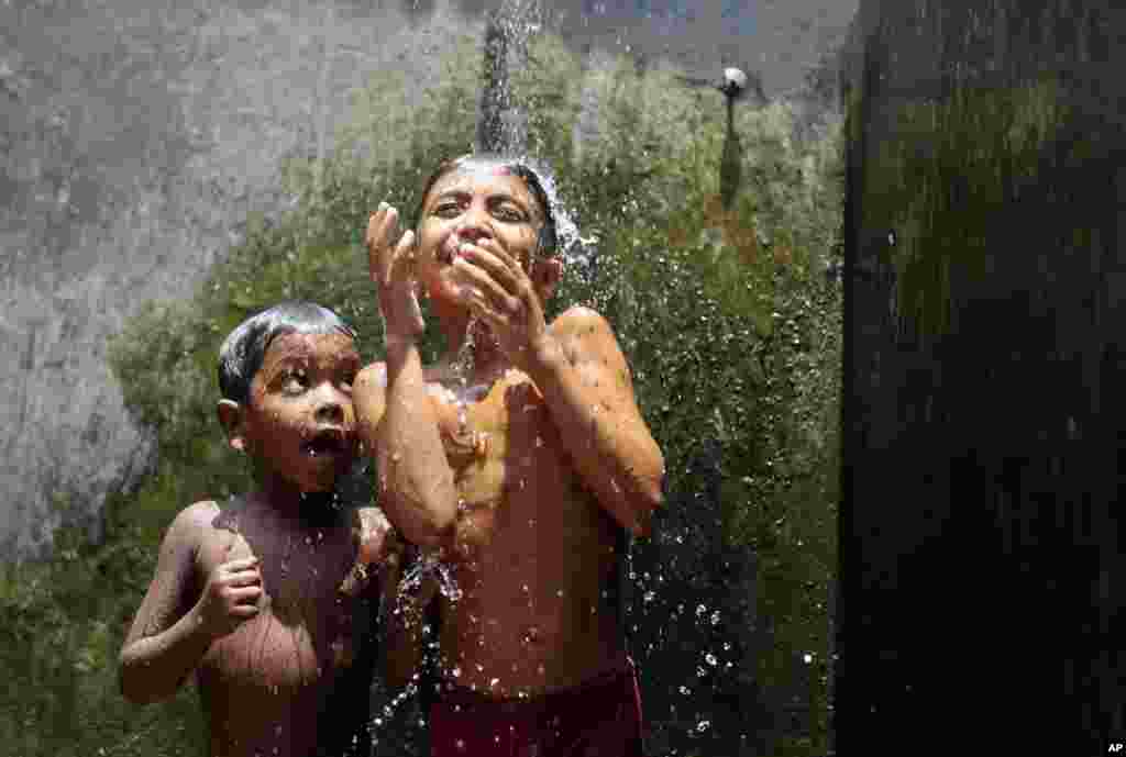 Bangladeshi children cool off at Mohammadpur Geneva camp, one of the largest refugee camps in Dhaka City.