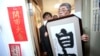 台北铜锣湾书店创办人林荣基手持台湾公民参与协会理事长何宗勋写的“自由”字画。