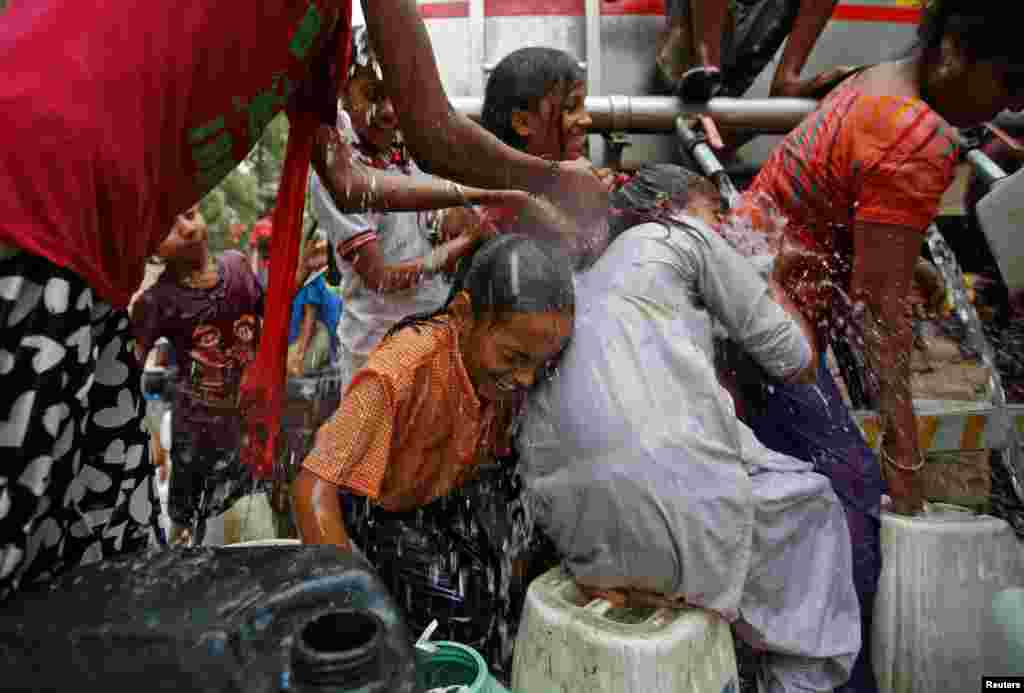 Anak-anak perempuan basah kuyup ketika mereka mencoba untuk mengisi wadah-wadah air yang kosong dengan air yang dibagikan oleh tanki pemerintah kota di suatu hari musim panas yang menyengat di New Delhi, India.