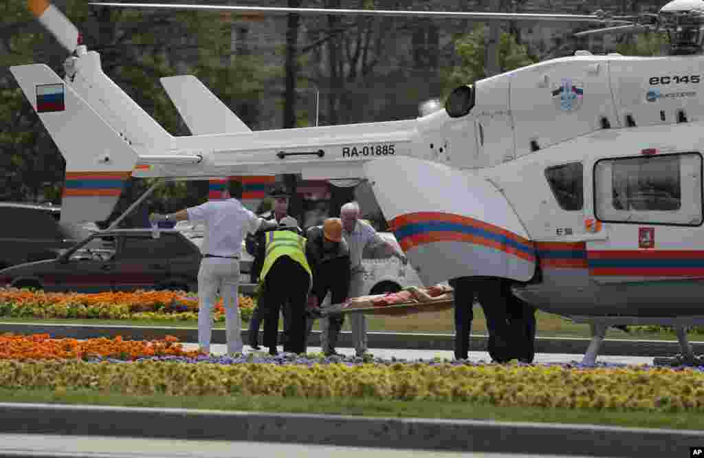 Petugas paramedik membawa seorang perempuan yang terluka ke sebuah helikopter medis di Moskow (15/7). (AP/Ivan Sekretarev)