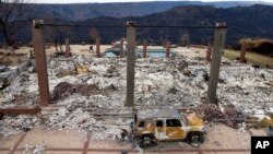 FILE - A vehicle rests in front of a home leveled by the Camp Fire in Paradise, Calif., Dec. 3, 2018. Authorities estimate it will cost at least $3 billion to clear debris of 19,000 homes destroyed by California wildfires last month.