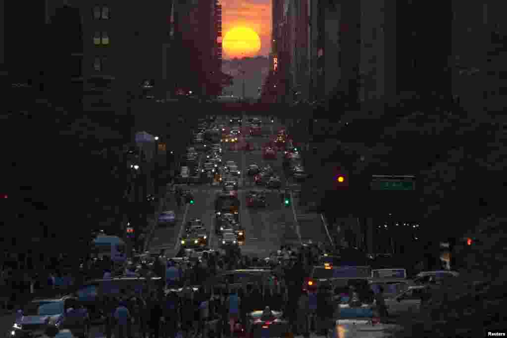 Orang-orang mengambil gambar matahari terbenam di jalan 42 kota New York, saat terjadinya "Manhattanhenge" yang berlangsung setiap dua tahun, 29 Mei 2013.