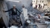 People gather near the rubble of houses destroyed by Saudi airstrikes near the airport in Sana'a, Yemen, March 31, 2015. 