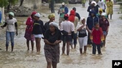 Residents leave flooded homes in a low lying area affected by Tropical Storm Isaac in Port-au-Prince, Haiti Aug. 25, 2012 (UN photo)