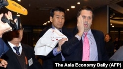 美国驻韩国大使李柏特(右)用手按住脸部刀伤离开世宗文化会馆