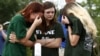 FILE - Mourners gather at a makeshift memorial left in memory of the victims killed in a shooting at Santa Fe High School in Santa Fe, Texas, May 21, 2018. 