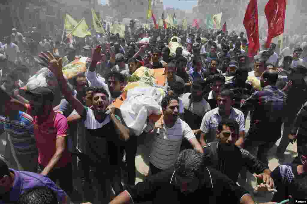 Masyarakat Palestina membawa jenazah para anggota keluarga Kaware, yang menurut para pejabat rumah sakit tewas dalam sebuah serangan udara Israel yang menimpa rumah mereka, dalam upacara pemakaman di Khan Younis di Jalur Gaza (9/7).