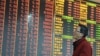 An investor looks at an electronic board showing stock information at a brokerage house in Hangzhou, Zhejiang province, China, December 14, 2012. 