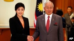 PM Thailand Yingluck Shinawatra (kiri) dan PM Malaysia Najib Razak berpose untuk para wartawan seusai menggelar konferensi pers di kantor PM Malaysia di Putrajaya, Malaysia (28/2).