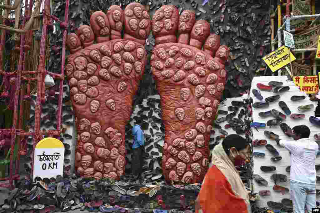 A person walk past workers decorating of a makeshift place of worship for Durga Puja with a theme in support the ongoing farmers protest against the central government's agricultural reforms, in Kolkata, India.
