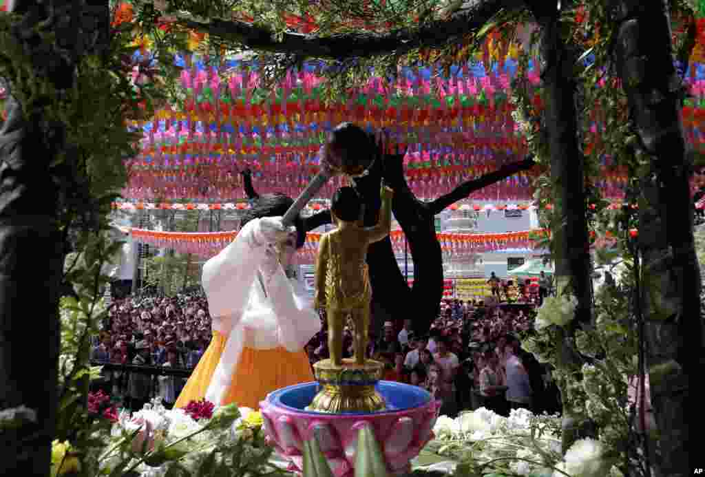 Seorang perempuan Korea menuangkan air suci ke sebuah patung Budha kecil untuk memperingati hari kelahiran Budha di Kuil Jogye di Seoul Korea.
