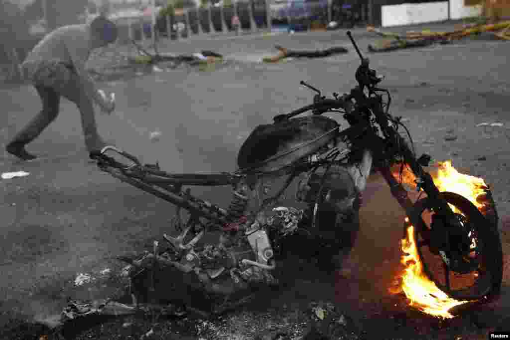 An anti-government demonstrator walks behind a burning motorcycle during a protest in San Cristobal, Venezuela, Feb. 27, 2014.