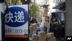 中国“光棍节”当天，北京街头快递小哥在分发运送包裹（2019年11月11日 美联社资料照）