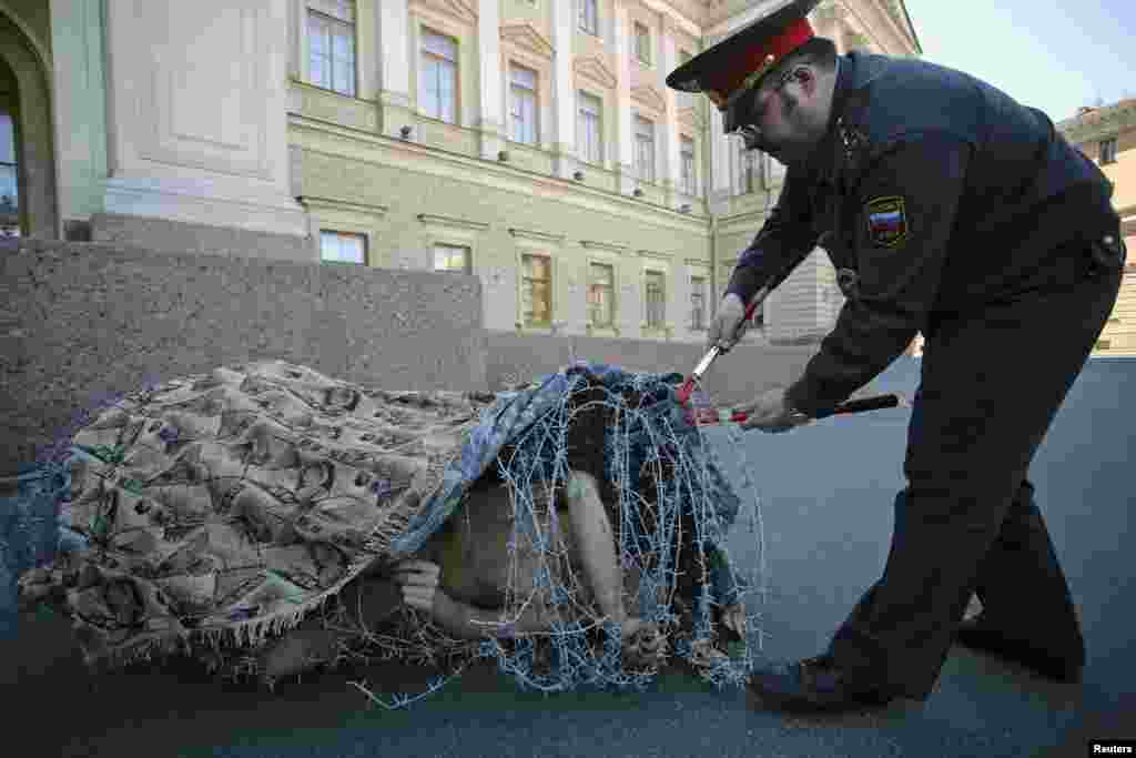 Artis Pyotr Pavlensky membungkus dirinya dalam gulungan kawat berduri, dalam sebuah aksi protes di depan markas Majelis Legislatif Saint Petersburg, Saint Petersburg, Rusia, sebagai ungkapan protes atas sistem legislatif kota itu yang menindas, seperti diberitakan oleh media lokal.