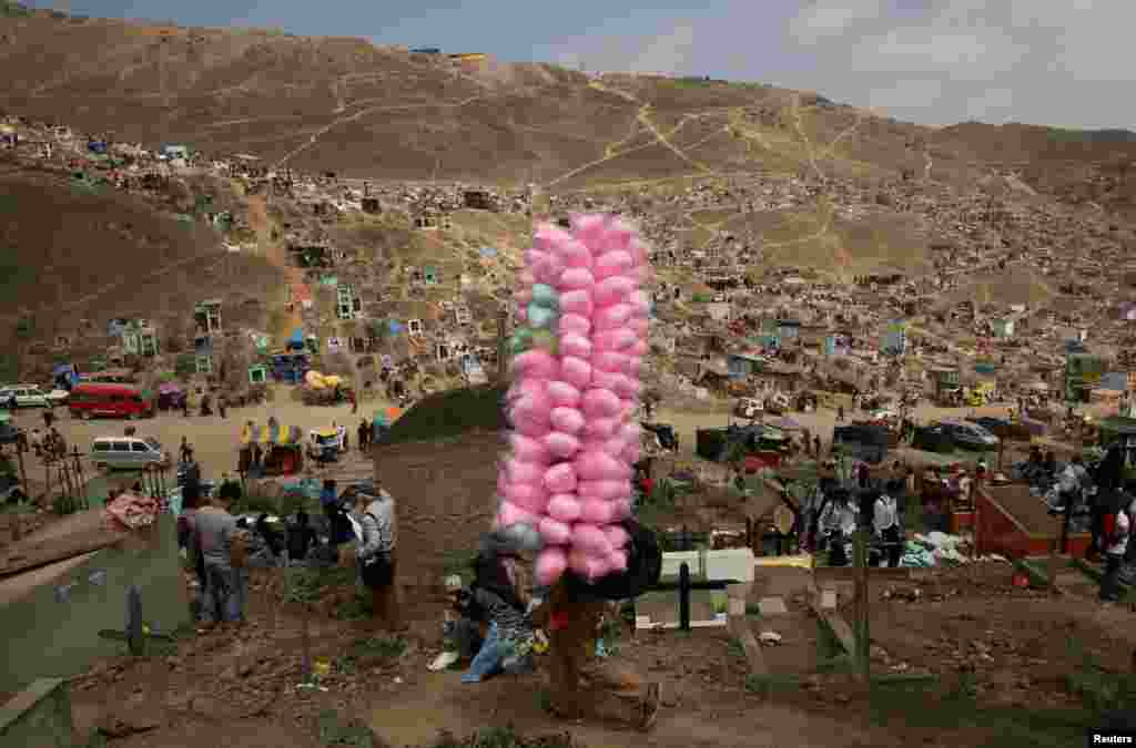 A street vendor sells cotton candy as people visit tombs of relatives and friends at 'Nueva Esperanza' (New Hope) cemetery during the Day of the Dead celebrations in Villa Maria del Triunfo on the outskirts of Lima, Peru, Nov. 1, 2016.