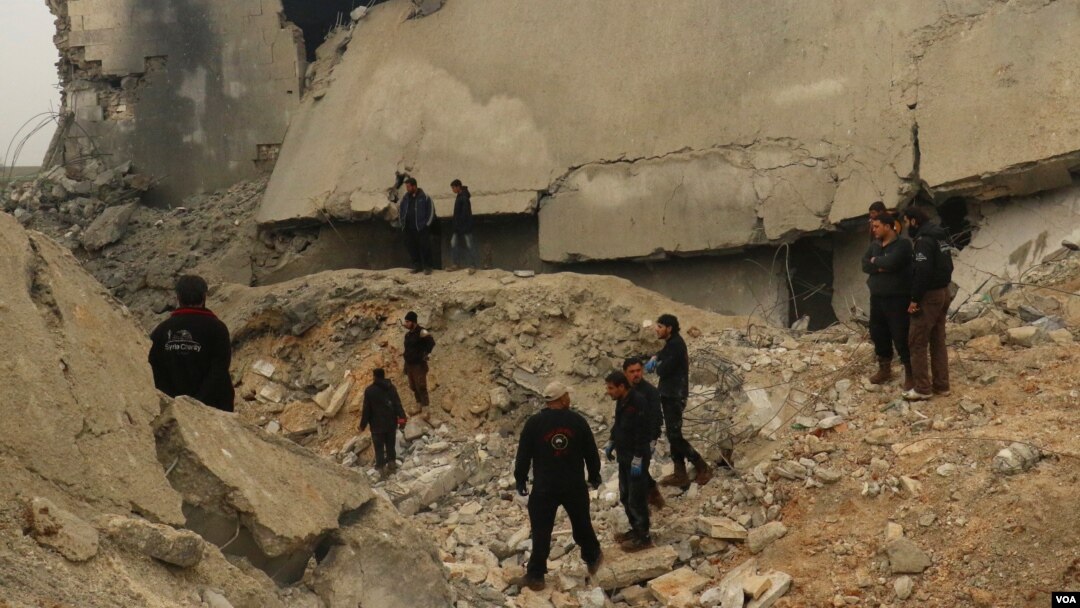 Miembros de la Defensa Civil de Siria y otras personas inspeccionan los daños a una mezquita en al-Jinah después de un ataque aéreo que dejó varios muertos civiles. Marzo 17, 2017.