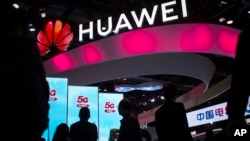 2019年10月31日，在北京的PT博览会上，与会者走过中国科技公司华为的5G服务展示台（美联社）。