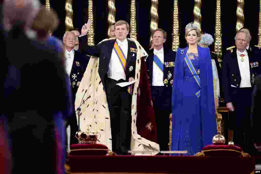 Willem-Alexander (kiri) mengangkat tangannya saat diambil sumpahnya sebagai Raja baru Belanda, didampingi isterinya, Ratu Maxima, di gereja Nieuwe Kerk, Amsterdam. 