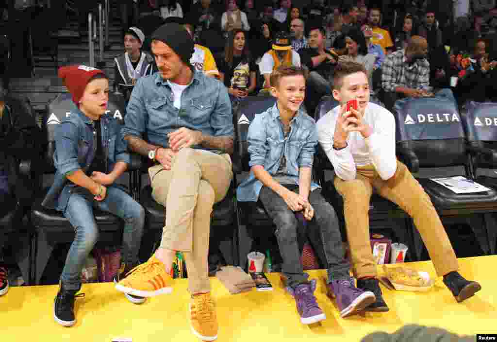 Beckham duduk di tepi lapangan bola basket bersama anak-anaknya Cruz (kiri), Romeo (kedua dari kanan) dan Brooklyn sebelum pertandingan NBA antara Los Angeles Lakers dan Phoenix Suns di Los Angeles, 16 November 2012. (Reuters/Danny Moloshok)